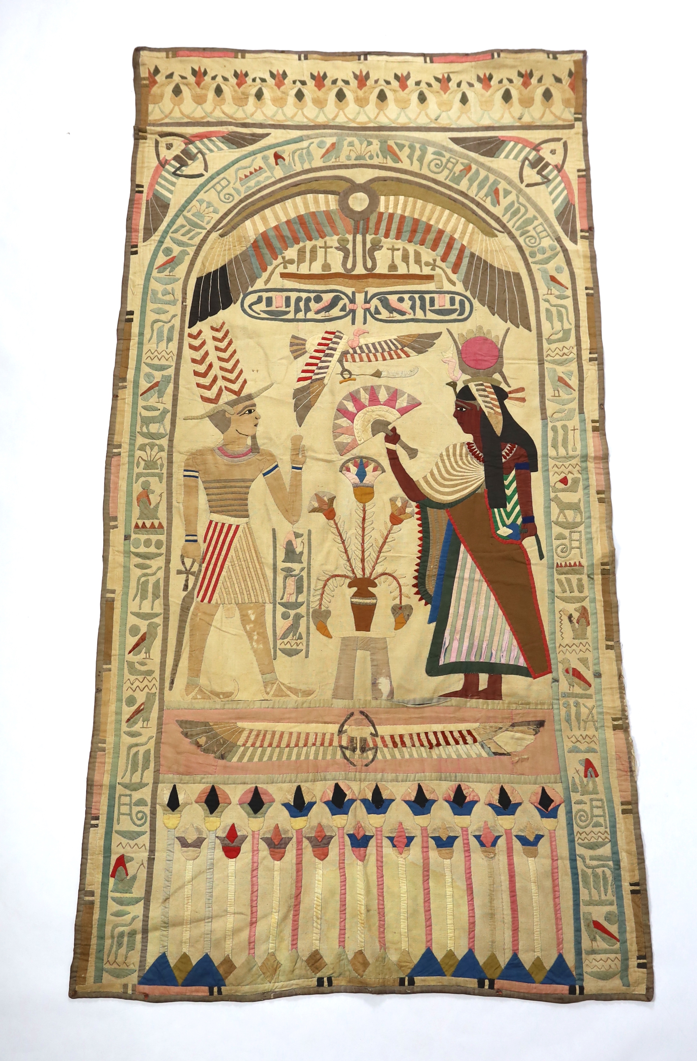 A 1930’s large Egyptian appliqué wall hanging, depicting Wadjet, (Goddess and protector of Kings) and Amun (God of wind) surrounded by hieroglyphic decorative symbols, 134cm wide x 268cm long